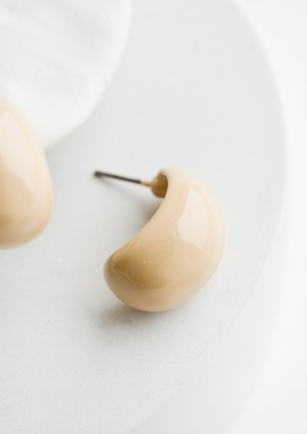 2: A pair of glossy ivory bean shaped earrings.
