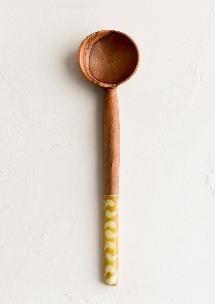 An olivewood coffee scoop with gold and white printed bone handle.