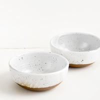 3: Two glossy white ceramic bowls with brown speckles.