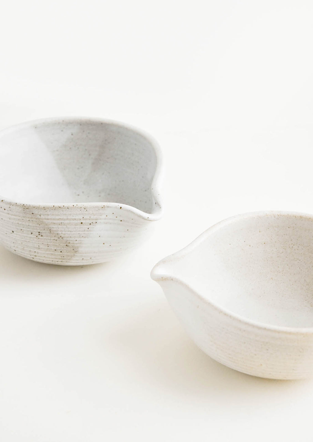 1: Two ceramic spouted bowls in different shades of white.