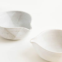 1: Two ceramic spouted bowls in different shades of white.