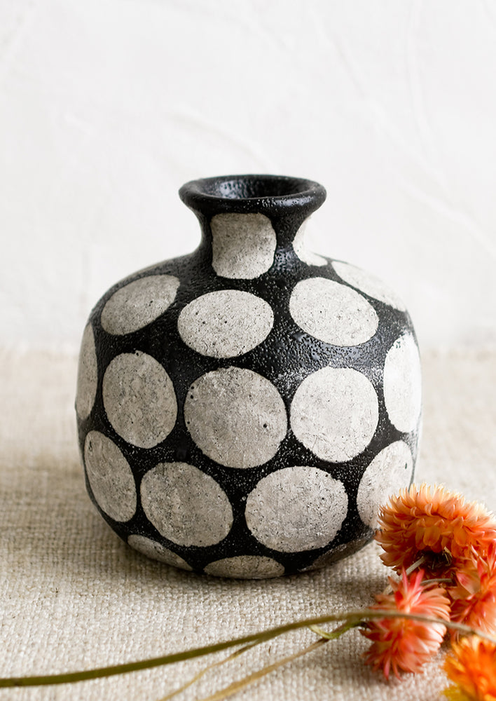 A round vase with narrow neck, in black with grey polka dot print.