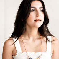 2: Model wears clay bead necklace and white tank top.