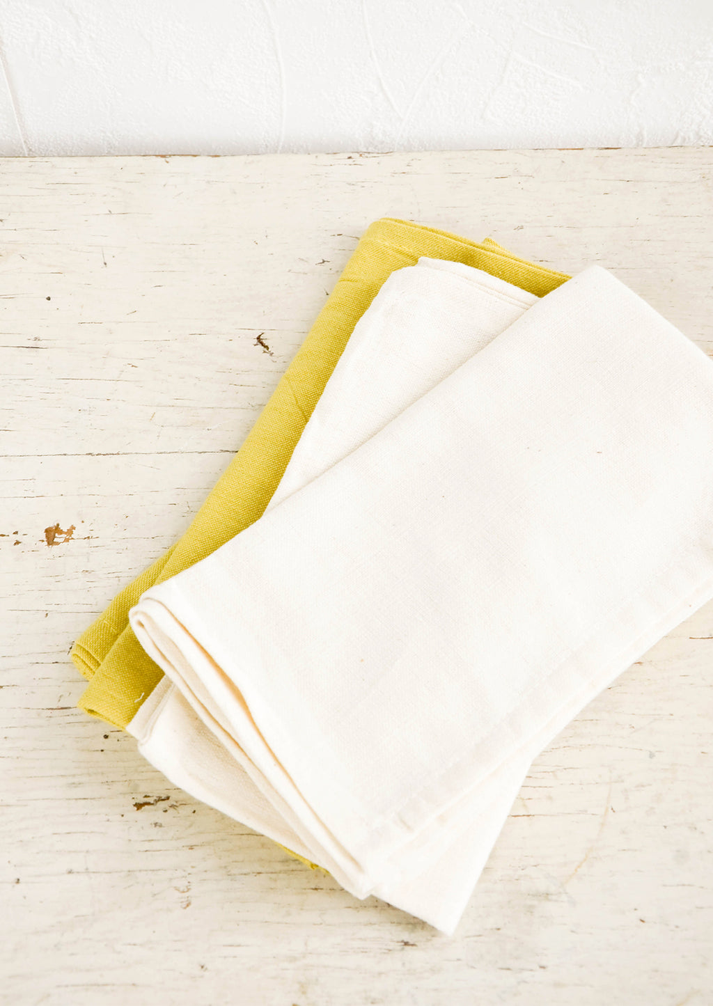 Natural: Folded cotton napkins in natural and chartreuse on a rustic table