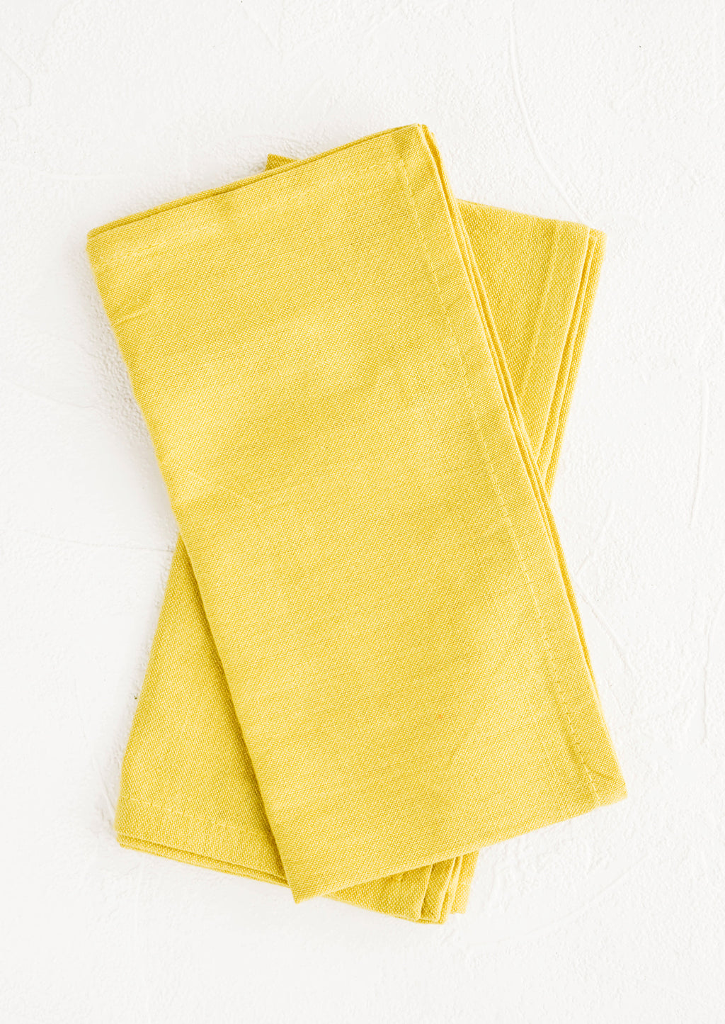 1: Pair of folded cotton napkins in chartreuse hue