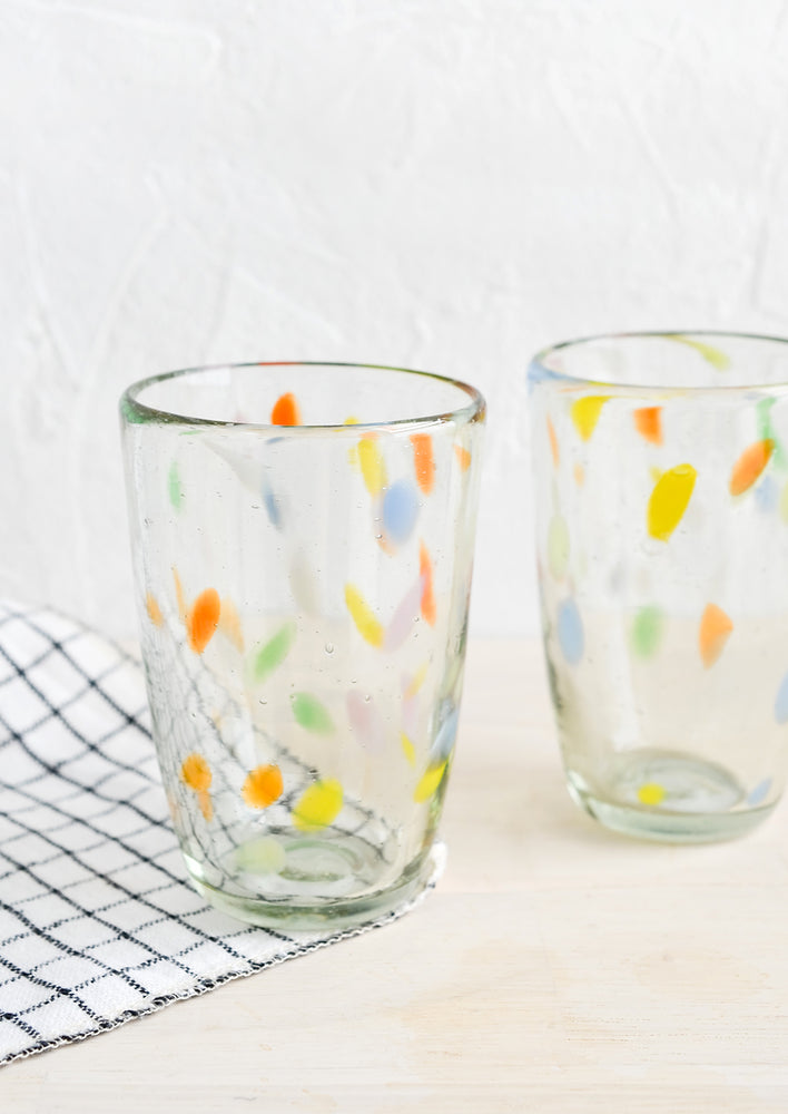 Two clear glass cups with flecks of color throughout.