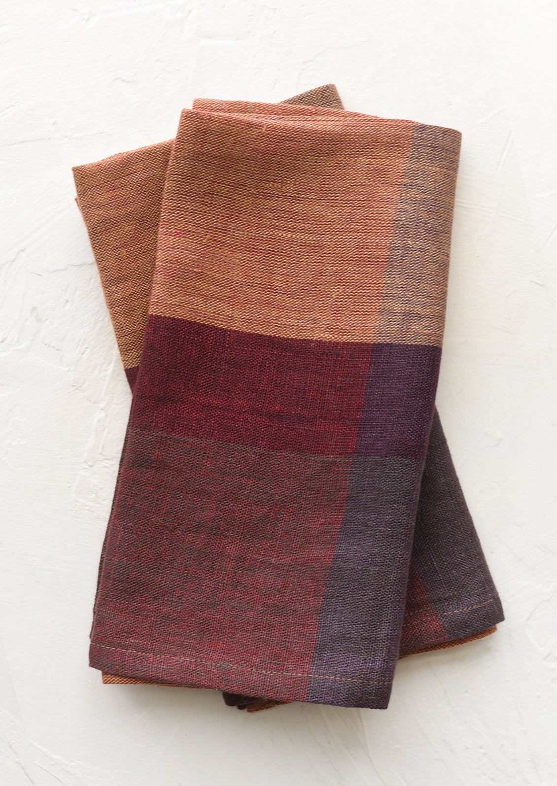 A pair of folded color overlay linen napkins.