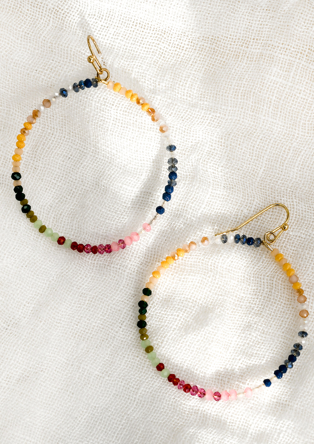 Muted Multi: A pair of beaded hoop earrings in assorted multi colors.