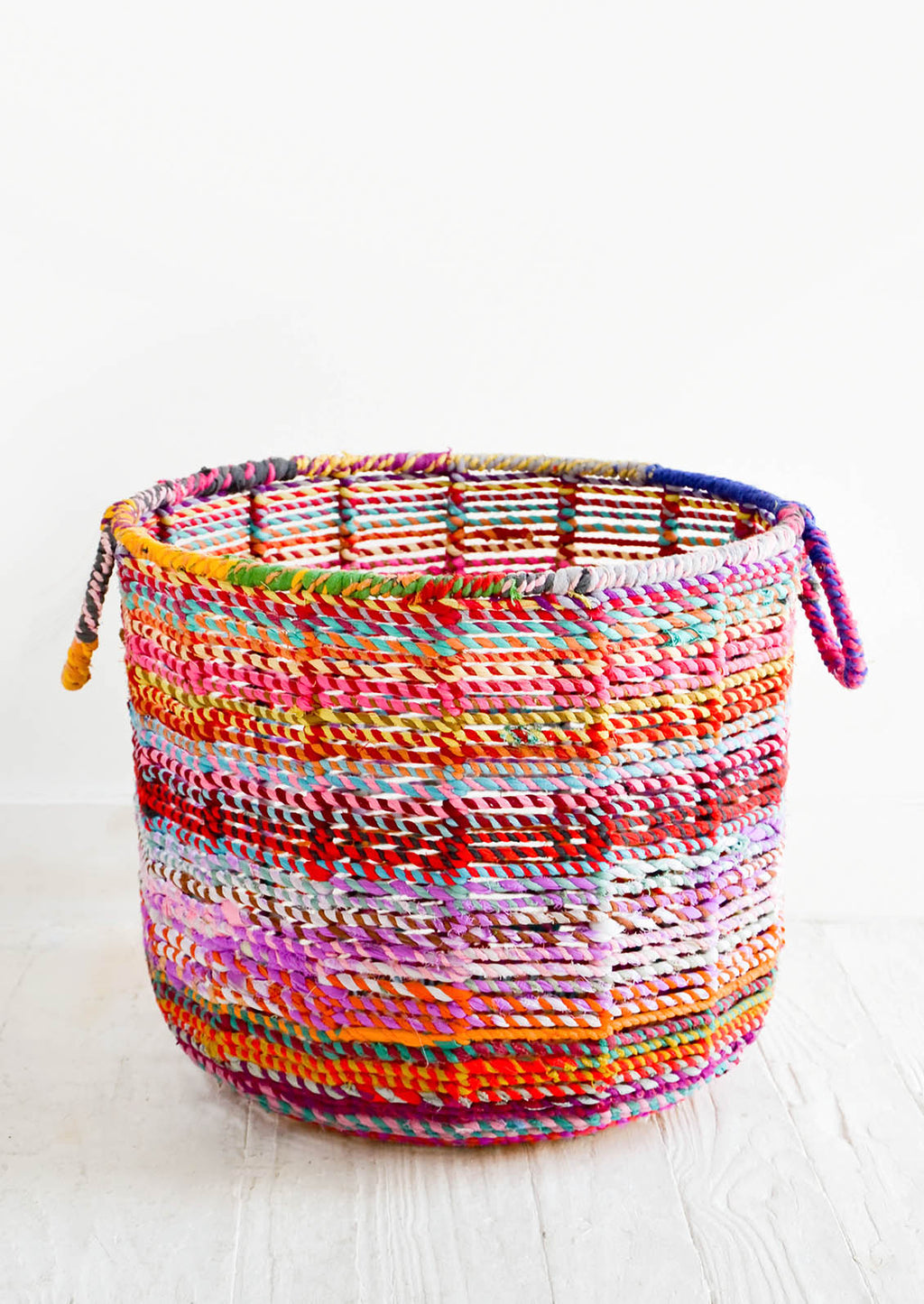 2: Round, circular storage bin made from colorful recycled fabrics woven together, featuring round handles at top.