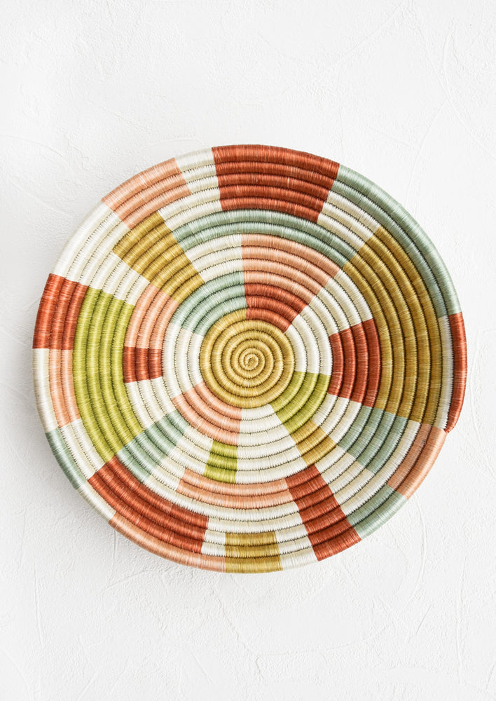 A large woven sweetgrass bowl in white with multicolor geometric design.