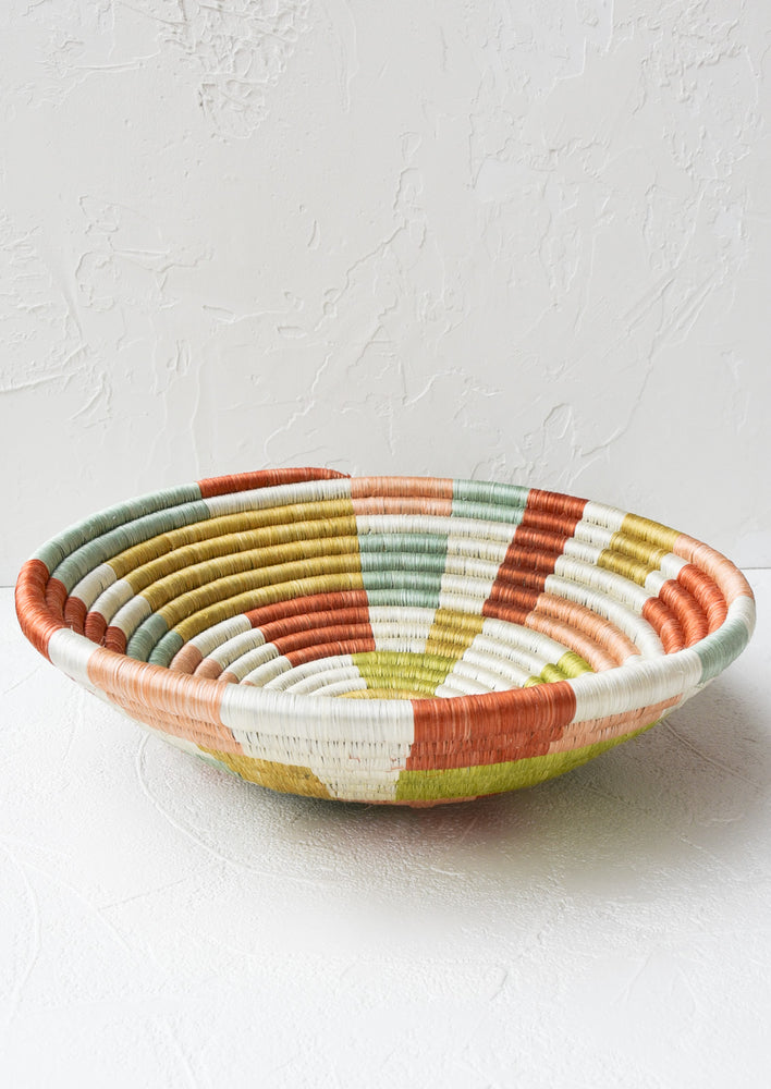 A large woven sweetgrass bowl in white with multicolor geometric design.