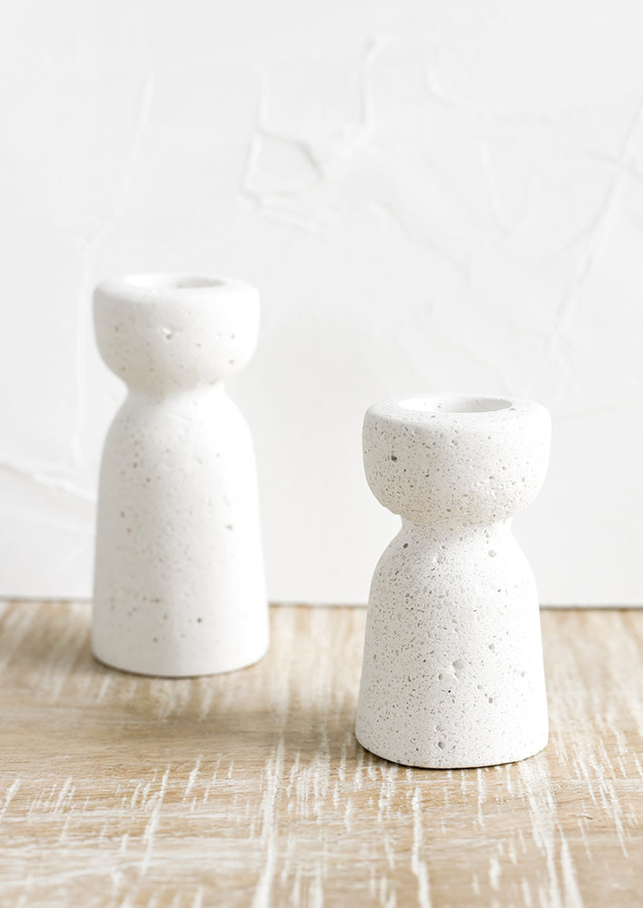 Two short and tall white concrete candleholders with pumice-like texture.