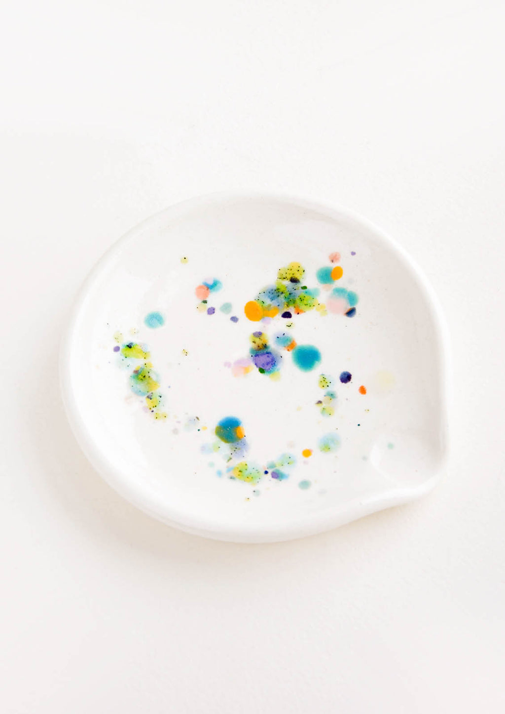 1: A round ceramic spoon rest with random, colorful glaze drips.