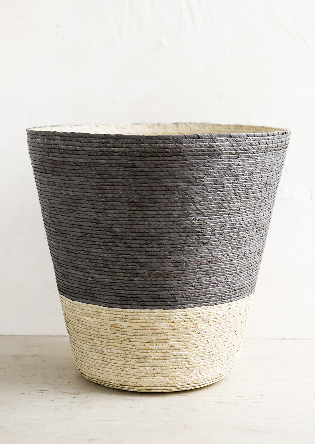 Mineral: A conical shaped storage basket made from woven palm leaf in mineral blue & natural color way.