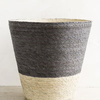 Mineral: A conical shaped storage basket made from woven palm leaf in mineral blue & natural color way.