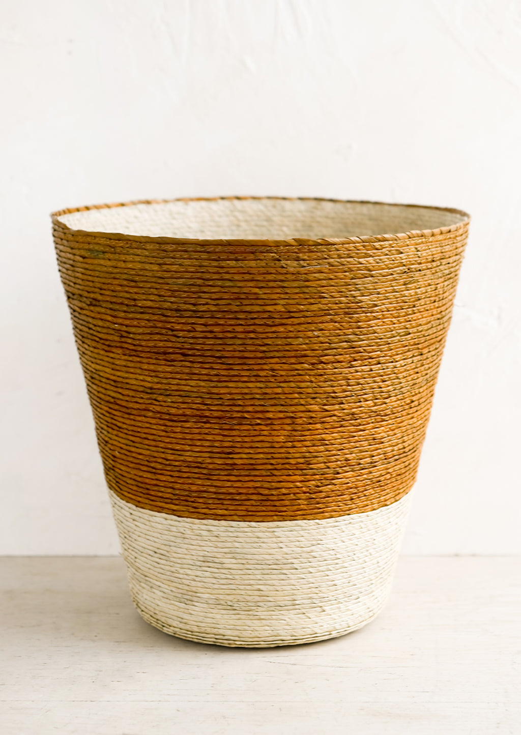Ochre: A conical shaped storage basket made from woven palm leaf in ochre & natural color way.