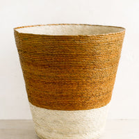 Ochre: A conical shaped storage basket made from woven palm leaf in ochre & natural color way.