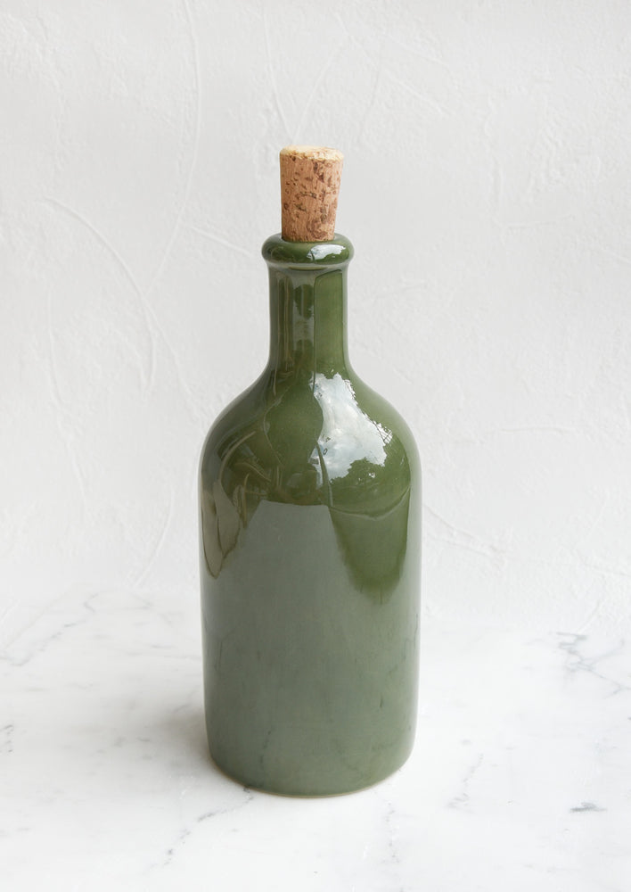 A glossy olive colored short bottle with cork top