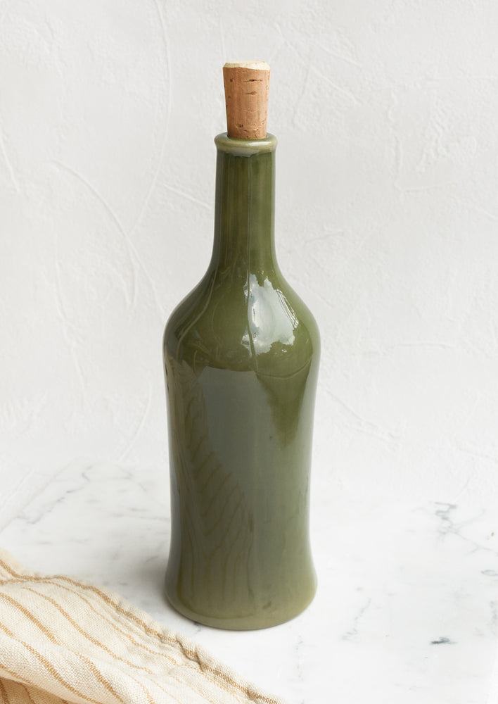 A glossy olive colored tall bottle with cork top