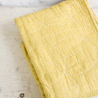 4: Chartreuse colored cotton throw with overlapping circle patterned embroidery, folded on table