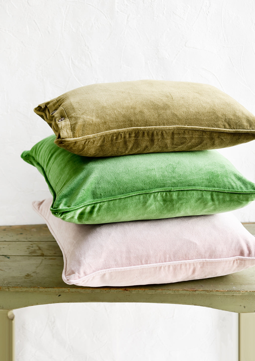 3: A stack of velvet pillows in green and pink.