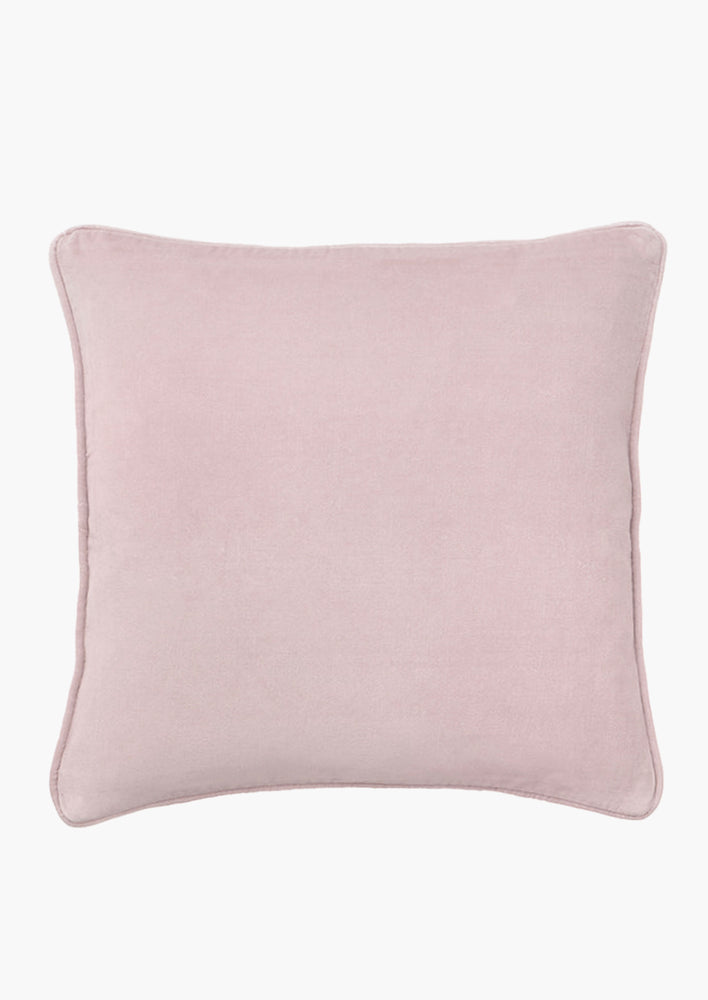 A square velvet throw pillow in dusty rose.