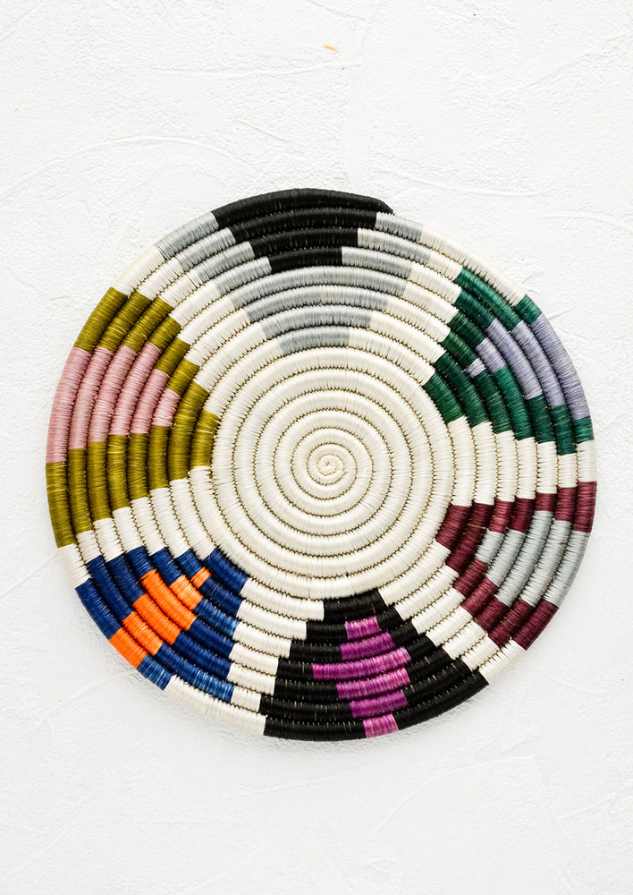 1: A round trivet made from woven raffia with colorful border design.
