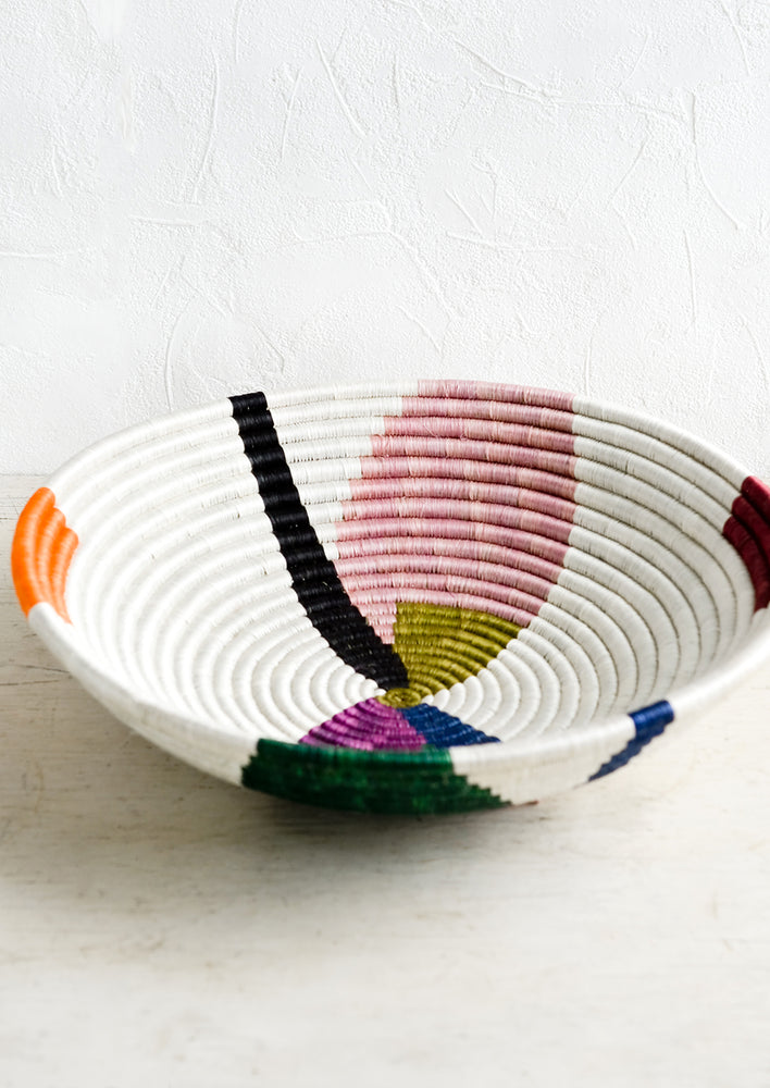 2: A large woven sweetgrass bowl in white with colorful abstract shapes.