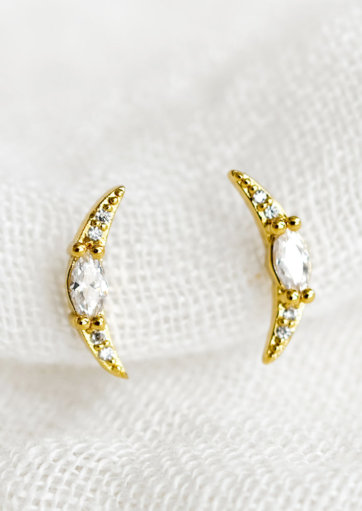 A pair of crescent shaped stud earrings with crystal detailing.