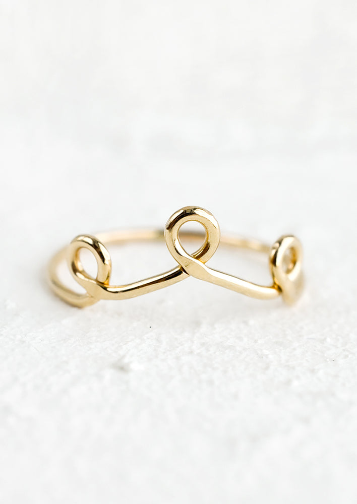 A gold stacking ring with three small loops resembling a crown.