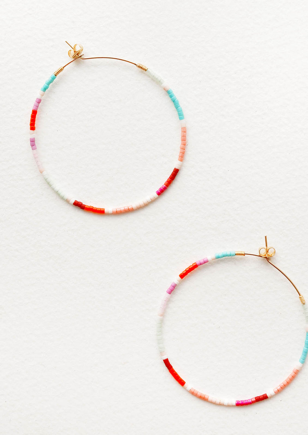 1: Delicate beaded hoop earrings of blue, orange, pink, white, and red glass beads on thin gold wire.