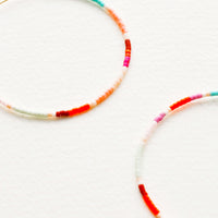 3: Close up detail of multi-colored beaded hoop earrings.