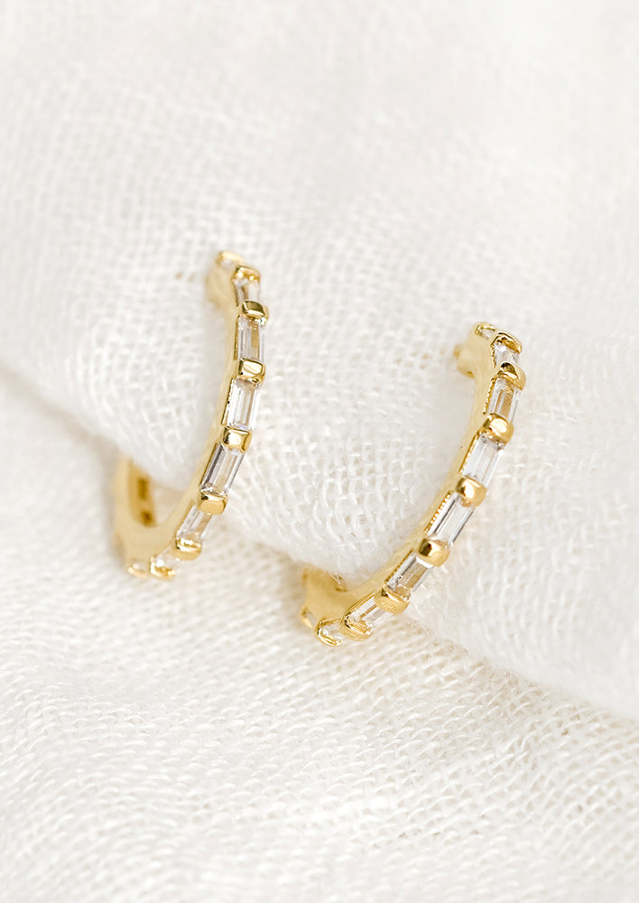 A pair of gold hoops with clear baguette shape crystals.