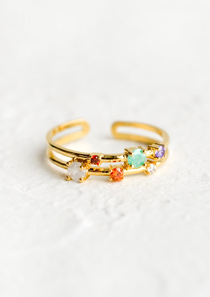 An open size gold ring with multicolor crystals in scattered arrangement.