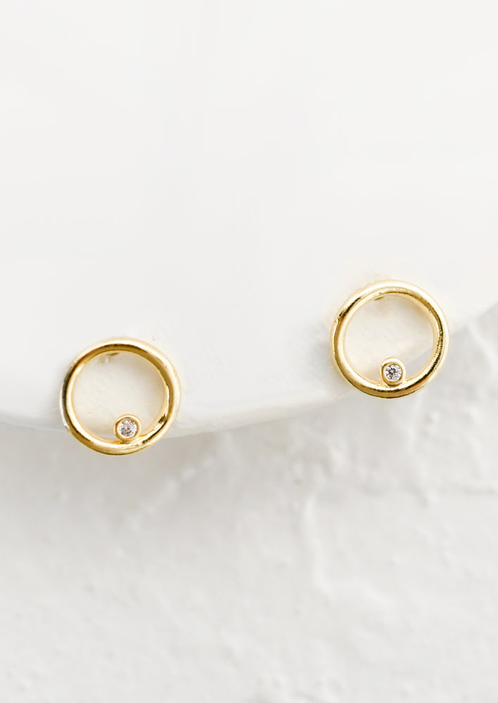 A pair of gold stud earrings in shape of hollow circle with single crystal detail.