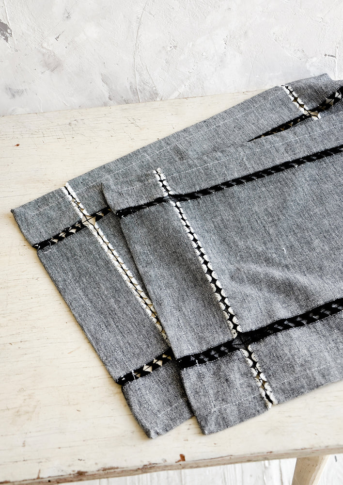 Pair of cotton placemats in black chambray with woven cutout strip detailing