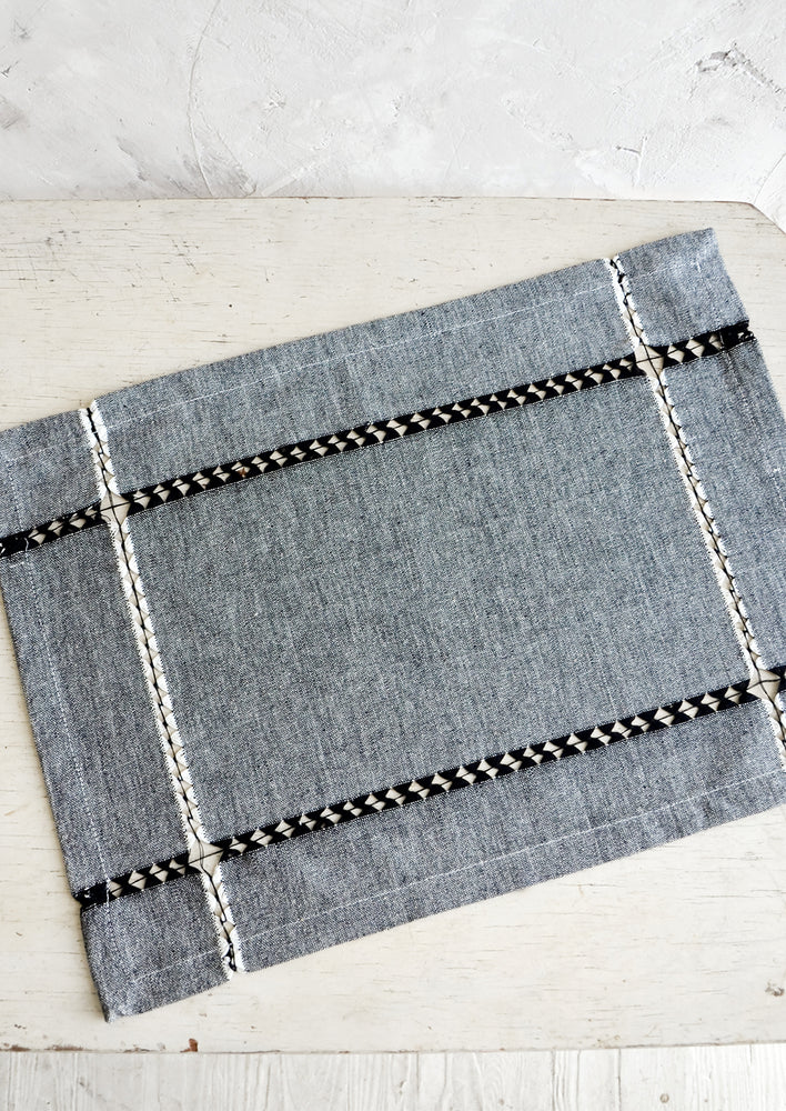 Cotton placemat in black chambray with woven cutout strip detailing