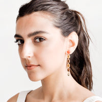2: Model wears glass crystal drop earrings and white tank top.