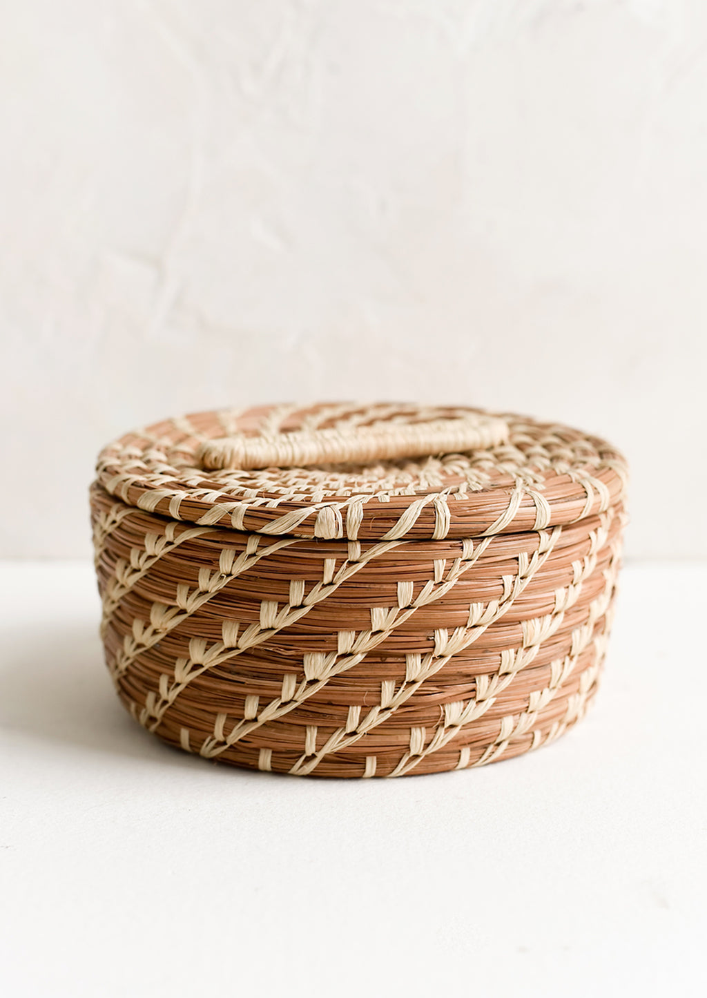 1: A small, round lidded basket made from woven pine needles.