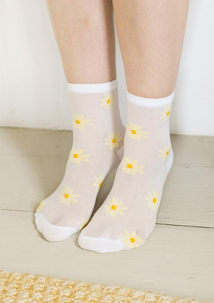 A person wearing white socks with yellow daisy pattern.