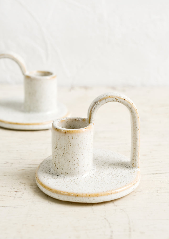 Ceramic taper holders with curved handle in speckled natural glaze.