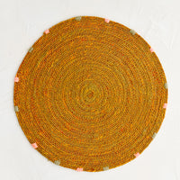 Ochre: A round seagrass placemat in ochre with grey and pink dashes embroidered around rim.