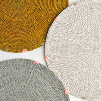1: Three round seagrass placemats in assorted colors.