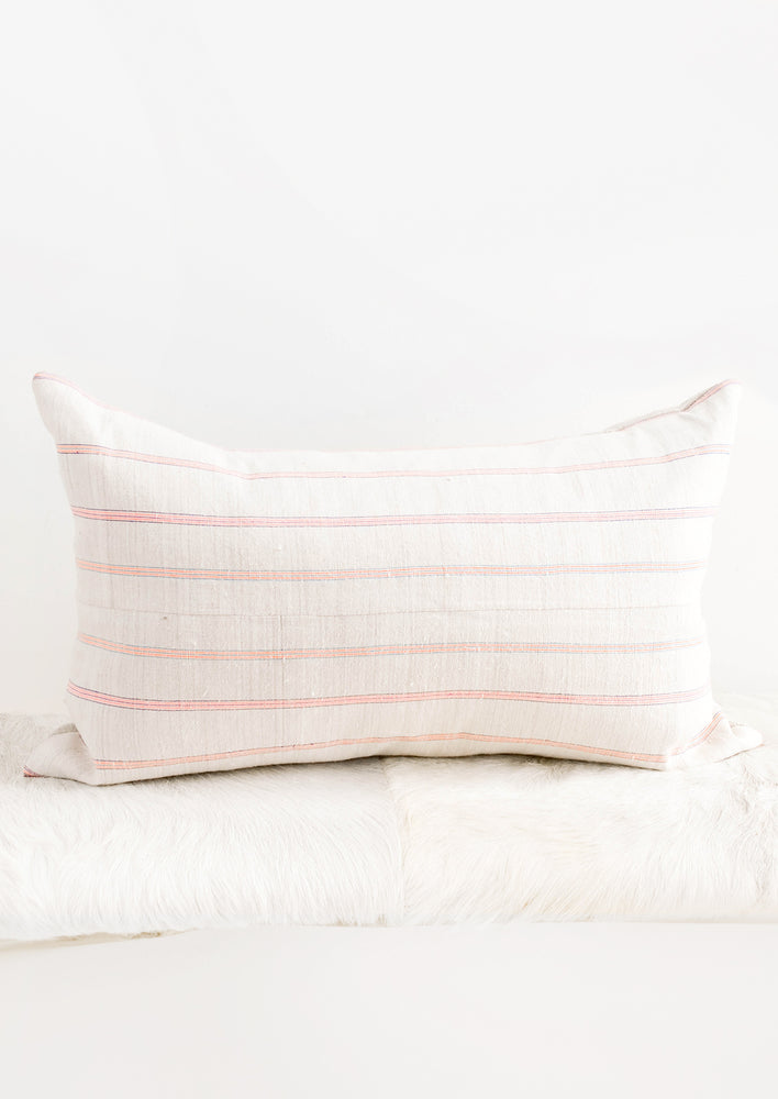 Rectangular throw pillow in light fabric with horizontal neon stripes
