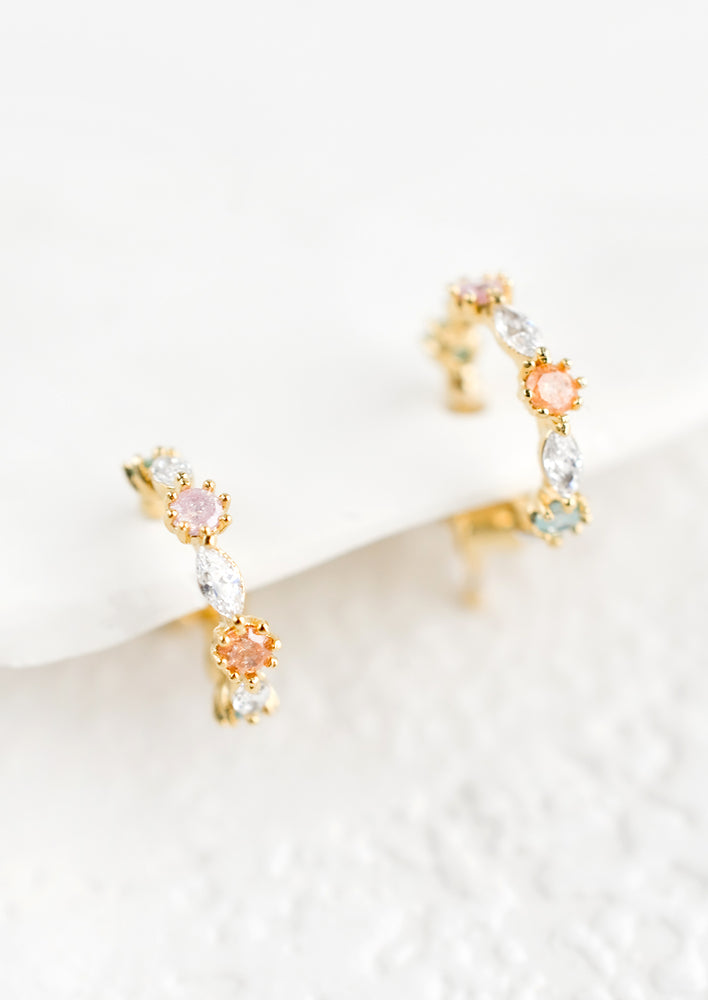 1: A small pair of huggie hoop earrings in pastel crystals.