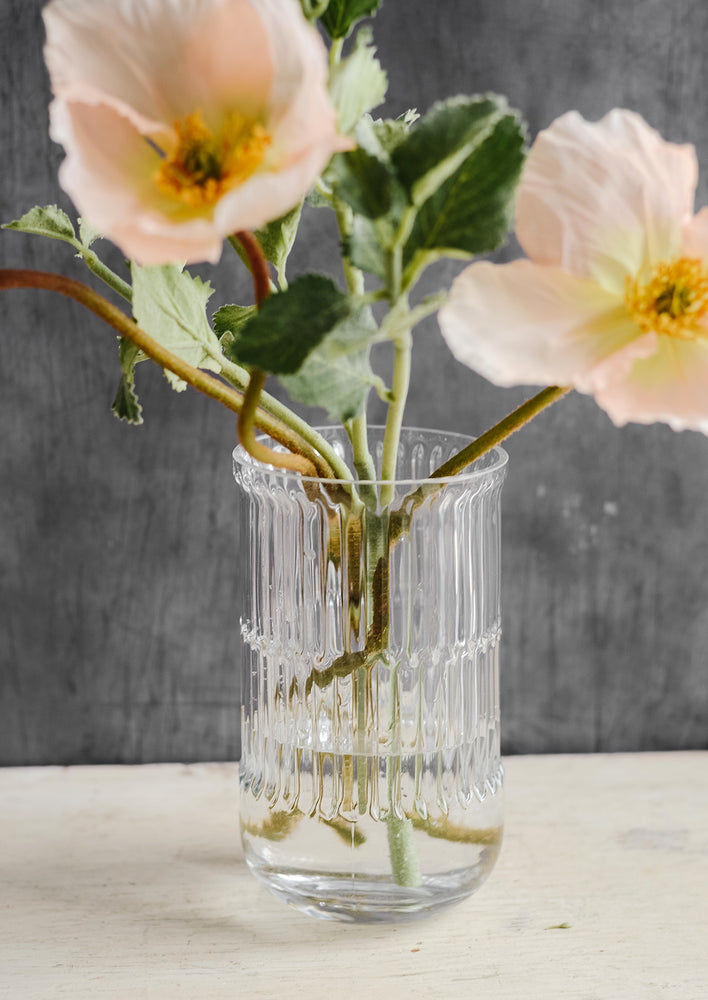 A textured clear glass vase with poppy flowers.
