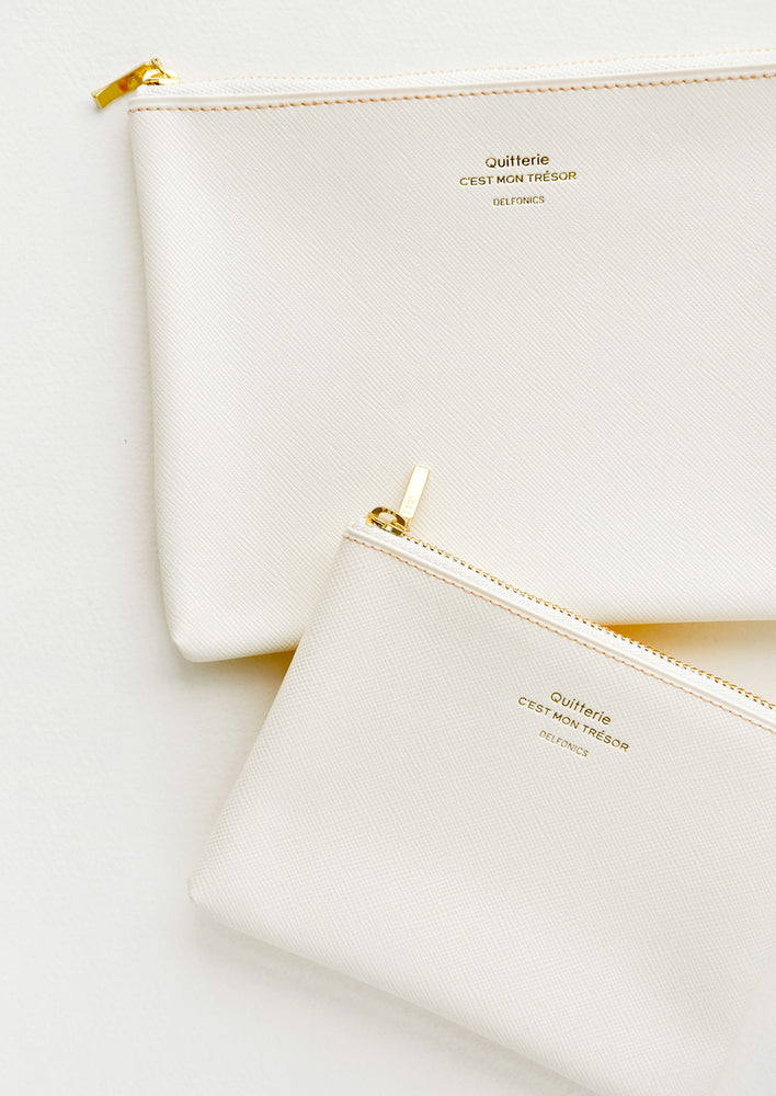 Cream / Small: Medium and small vinyl pouches with gold zipper and crosshatch texture, in cream.