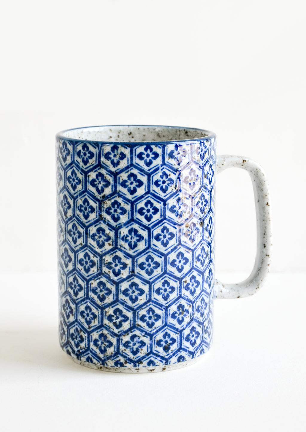 Hexagonal Floral: A tall mug with handle made from speckled grey ceramic with hexagonal indigo tile pattern throughout.