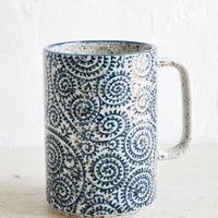 Paisley Swirl: A tall mug with handle made from speckled grey ceramic with indigo paisley pattern throughout.