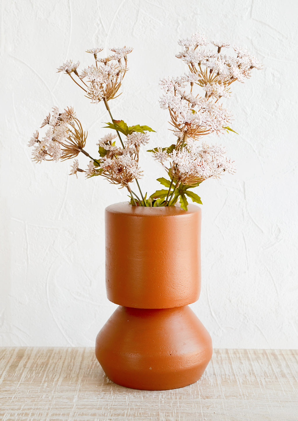 2: A terracotta vase with shapely silhouette, holding flowers.
